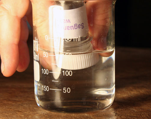 reaching into beaker to unscrew cap from large test tube
