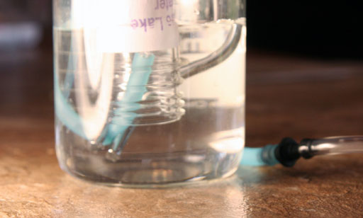 tubing directed into test tube using metal tongs