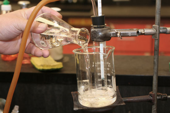 beaker on stand with test tube in it. Test tube held by clamp